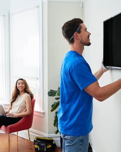 Professional TV mounting Dubai technician installing a large smart TV on a wall bracket.