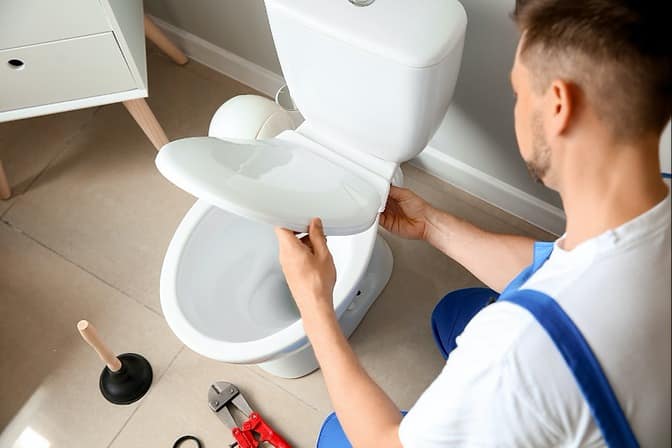 Expert plumber performing a WC fitting and toilet replacement in Dubai.